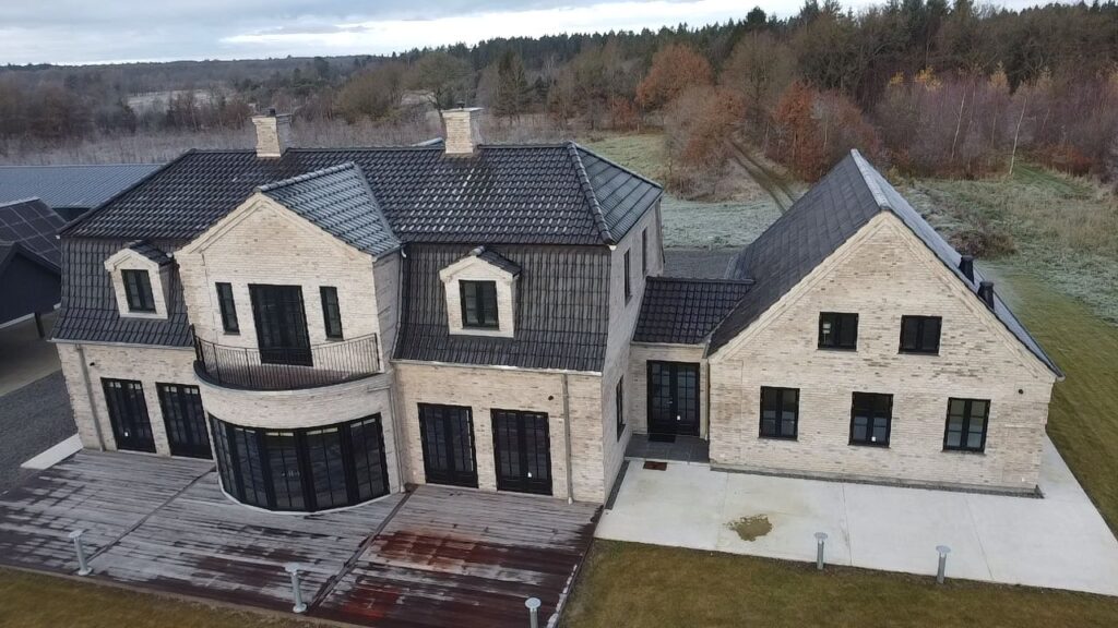Ny villa i lyse mursten med stor terrasse, set fra luften