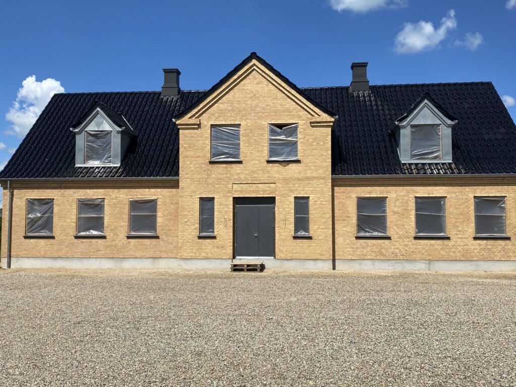 Facade på ny villa i gule mursten med kviste og skorstene