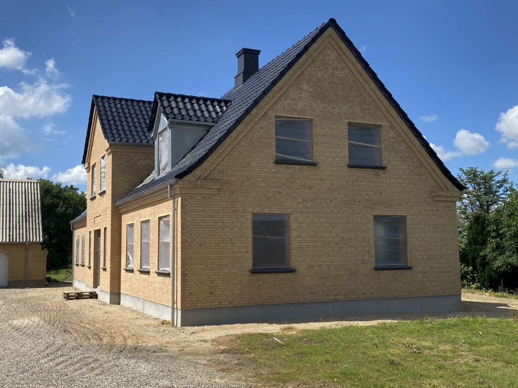 Gavl på ny villa i gule mursten med sort tegltag