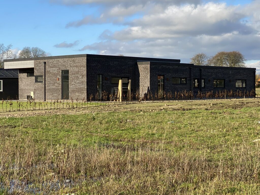 Langt nyt hus i mørke mursten med fladt tag