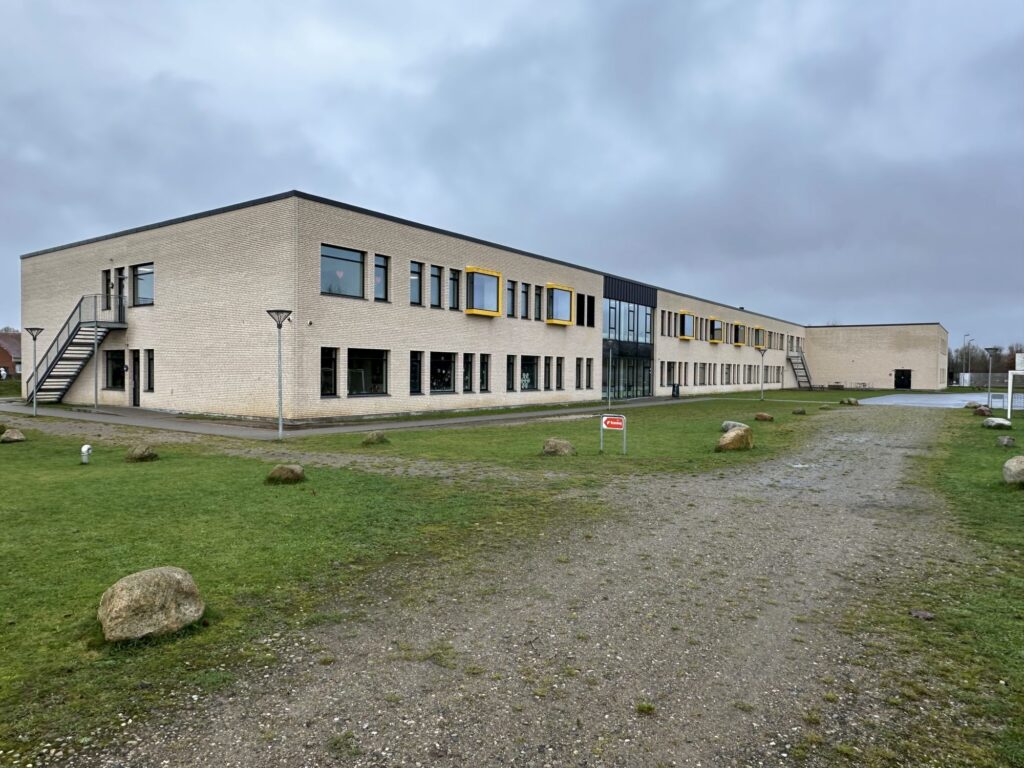Hærvejsskolens lange facade i lyse mursten med gule vinduesrammer