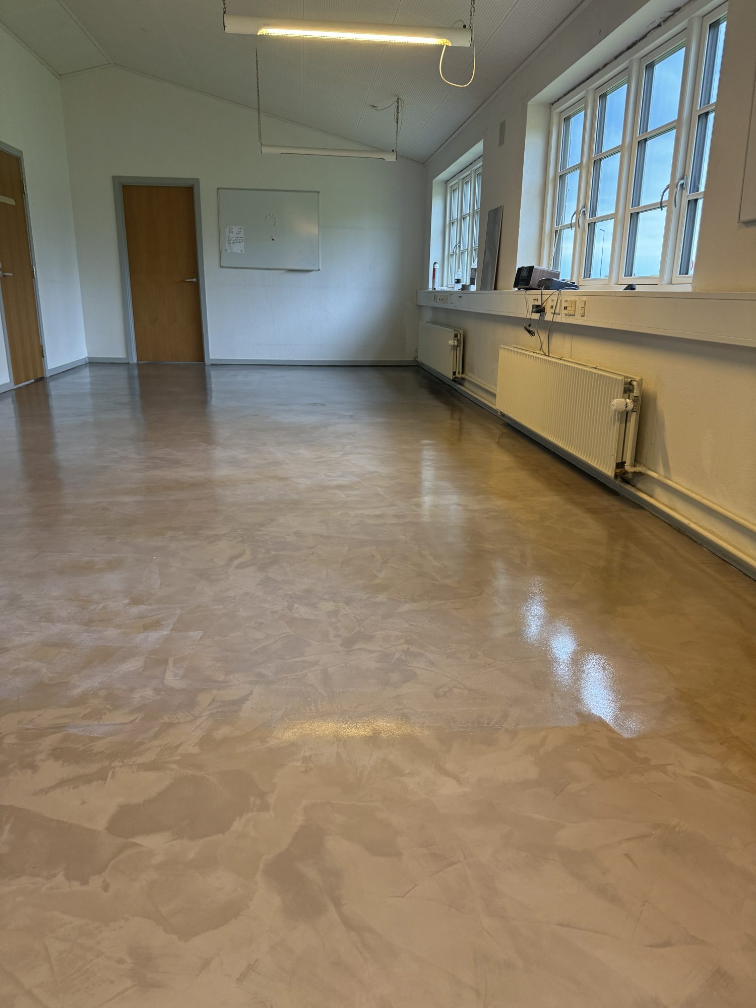 Microcementgulv med blank overflade og lys fra vinduerne